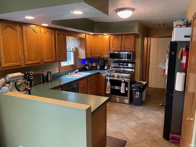 2006 Felix Pl, Plymouth, IN 46563 - kitchen featuring appliances with stainless steel finishes, brown cabinetry, a peninsula, recessed lighting, and a textured ceiling
