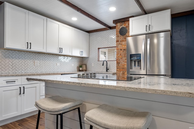 9462 W 1200 S 35, Marion, IN 46952 - kitchen with stainless steel refrigerator with ice dispenser, black electric stovetop, decorative backsplash, white cabinetry, and beam ceiling