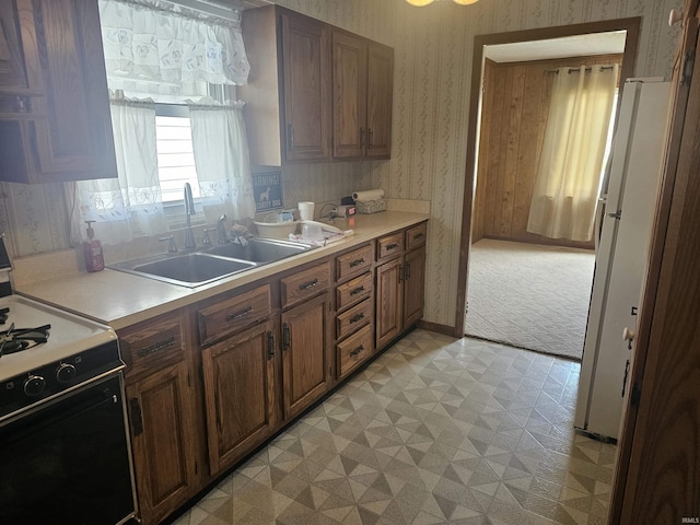 207 E Columbia St, Logansport, IN 46947 - kitchen featuring black gas range, light flooring, wallpapered walls, light countertops, and brown cabinetry
