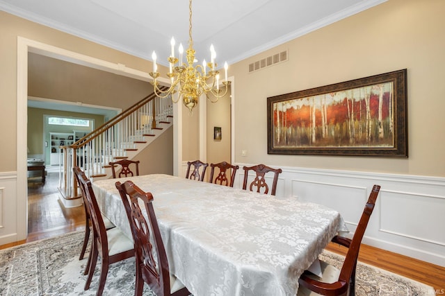 61705 Greentree Dr, South Bend, IN 46614 - dining room featuring wood finished floors, ornamental molding, stairs, a chandelier, and wainscoting