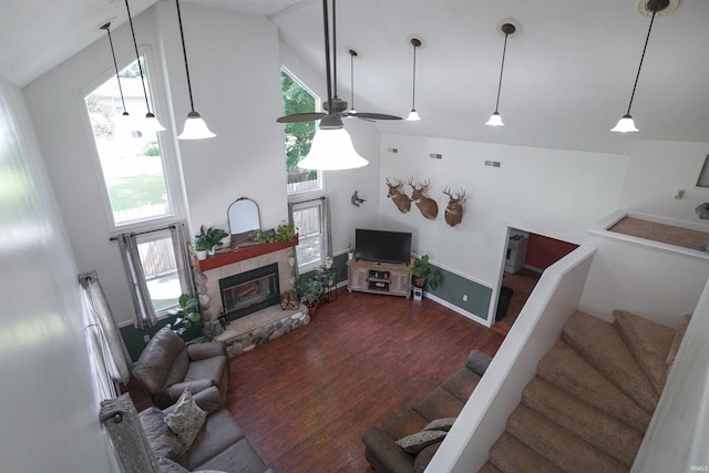 8558 E John Emery Rd, New Carlisle, IN 46552 - living room featuring wood finished floors, stairs, a ceiling fan, a stone fireplace, and high vaulted ceiling