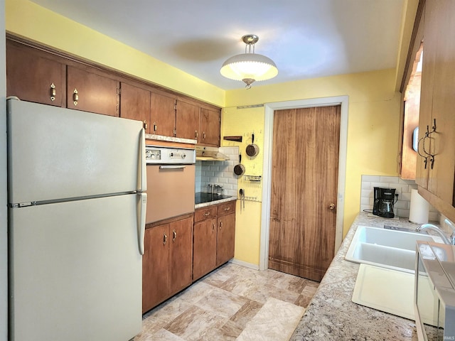 3315 E Paulding Rd, Fort Wayne, IN 46816 - kitchen with white appliances, backsplash, light countertops, brown cabinetry, and under cabinet range hood