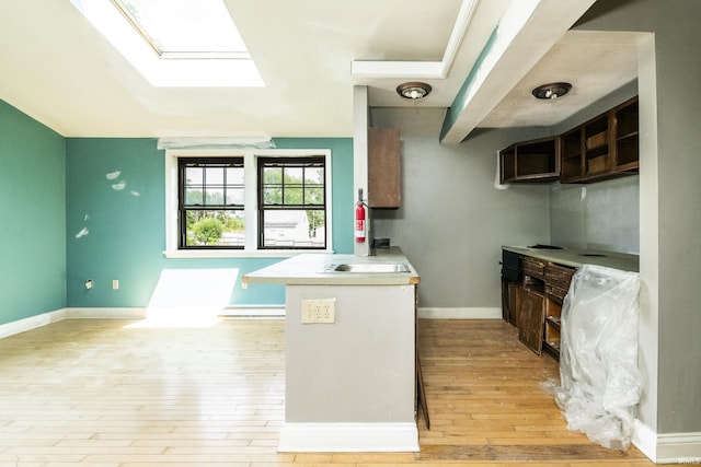 1121 W Grant St, Ellettsville, IN 47429 - kitchen featuring a skylight, light wood-style floors, a peninsula, and light countertops