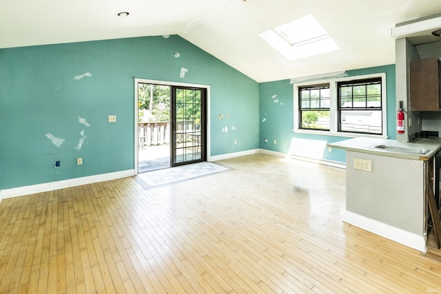 1121 W Grant St, Ellettsville, IN 47429 - unfurnished living room with lofted ceiling, a skylight, and light wood-style flooring