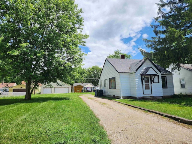 2206 S Hackley St, Muncie, IN 47302 - view of side of property with a yard, driveway, a chimney, a shingled roof, and a detached garage