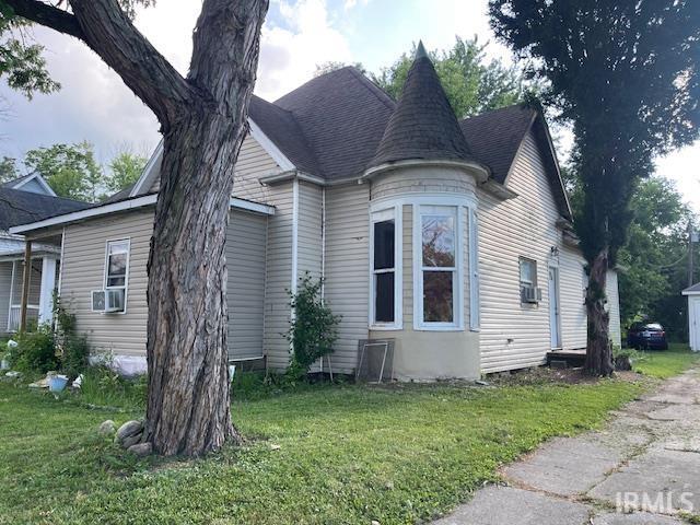 1919 Fletcher St, Anderson, IN 46016 - view of side of home with a yard, a shingled roof, and cooling unit