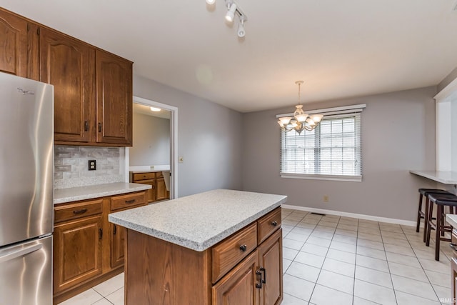 4301 W Friar Dr, Muncie, IN 47304 - kitchen featuring freestanding refrigerator, light tile patterned floors, light countertops, decorative backsplash, and a chandelier