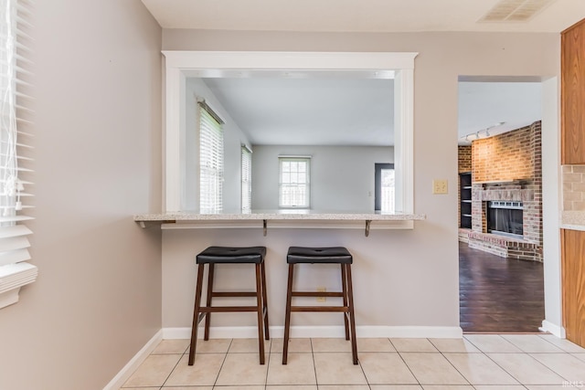 4301 W Friar Dr, Muncie, IN 47304 - kitchen featuring a kitchen bar, a brick fireplace, and light tile patterned flooring