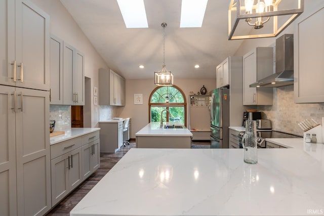4365 N Maple Grove Rd, Bloomington, IN 47404 - kitchen with wall chimney range hood, freestanding refrigerator, a kitchen island with sink, a skylight, and tasteful backsplash