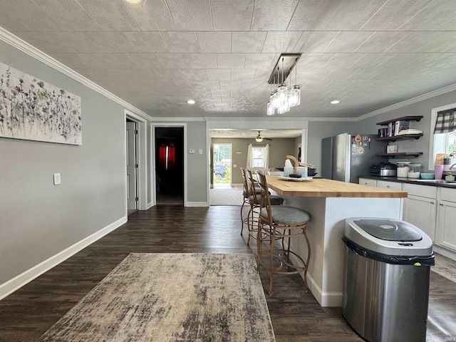 740 NW 3rd St, Linton, IN 47441 - kitchen featuring butcher block counters, freestanding refrigerator, a breakfast bar, crown molding, and dark wood finished floors
