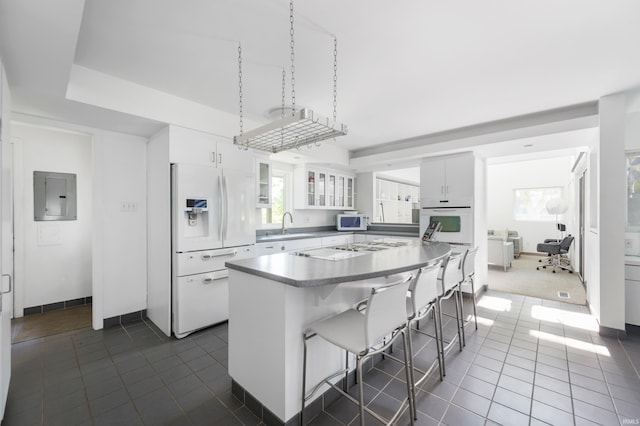 1144 N Warwick Rd, Muncie, IN 47304 - kitchen with white appliances, electric panel, dark tile patterned floors, a kitchen bar, and a center island