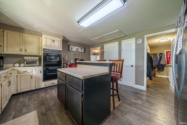 401 W Third St, Fairmount, IN 46928 - kitchen featuring light countertops, a kitchen island, a kitchen breakfast bar, and dark wood-type flooring
