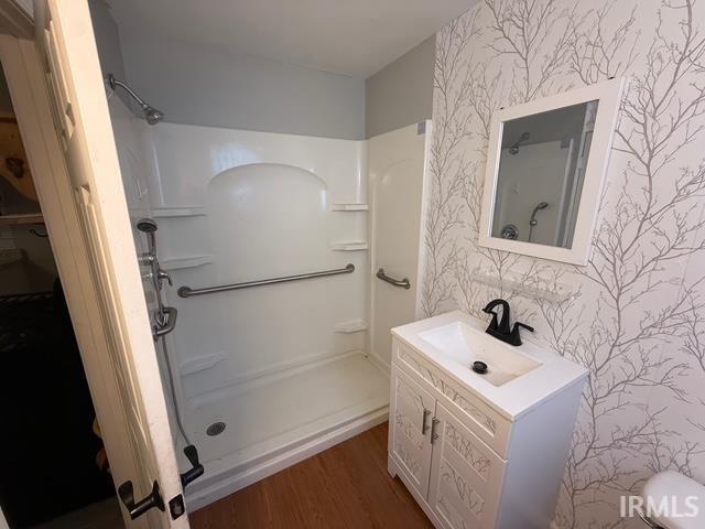 1021 W Franklin St, Evansville, IN 47710 - bathroom featuring wallpapered walls, a stall shower, vanity, and wood finished floors