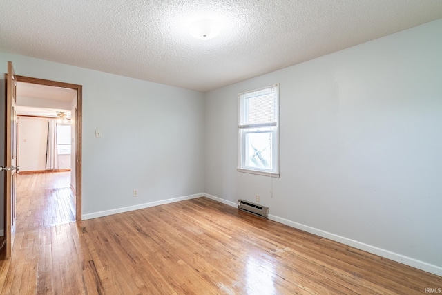 208 Chestnut St, Avilla, IN 46710 - unfurnished room with a baseboard heating unit, light wood-type flooring, and a textured ceiling