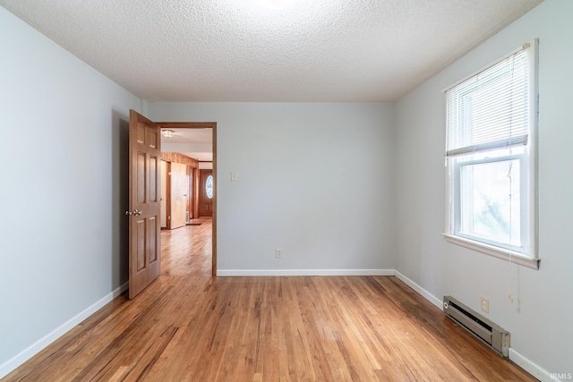 208 Chestnut St, Avilla, IN 46710 - spare room featuring a baseboard heating unit, light wood-type flooring, and a textured ceiling