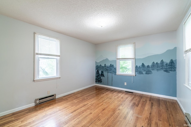 208 Chestnut St, Avilla, IN 46710 - empty room with a baseboard heating unit, light wood-type flooring, baseboard heating, and a textured ceiling