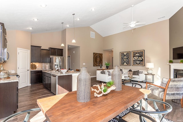 2057 Abbey Ln, Columbus, IN 47201 - dining area with ceiling fan, dark wood-type flooring, high vaulted ceiling, and a fireplace