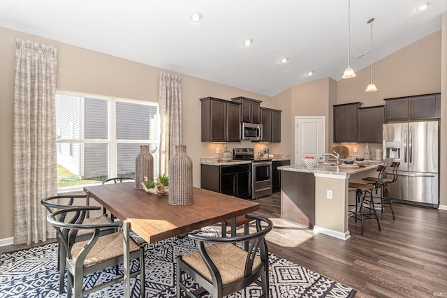 2057 Abbey Ln, Columbus, IN 47201 - kitchen featuring stainless steel appliances, dark brown cabinets, a center island with sink, dark wood-style flooring, and a breakfast bar area