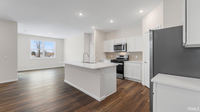 5103 Buffay Ct, New Haven, IN 46774 - kitchen featuring appliances with stainless steel finishes, backsplash, dark wood-type flooring, a center island with sink, and white cabinetry