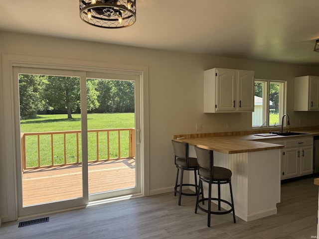 1501 S Wheeling St, Jonesboro, IN 46938 - kitchen with white cabinets, a breakfast bar, butcher block countertops, wood finished floors, and a peninsula