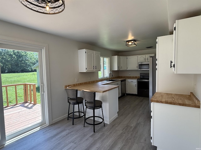 1501 S Wheeling St, Jonesboro, IN 46938 - kitchen featuring appliances with stainless steel finishes, a peninsula, white cabinets, wood finished floors, and wooden counters