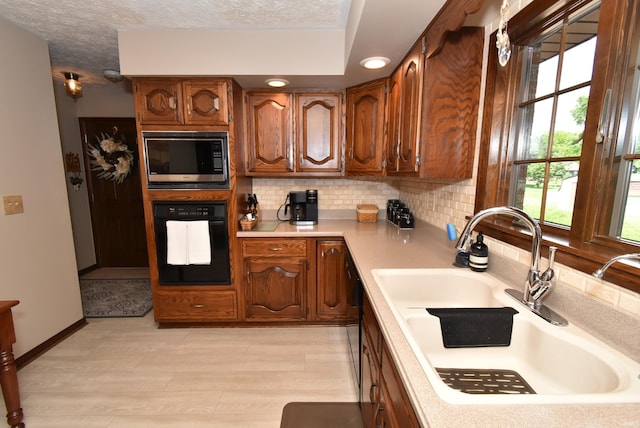 805 S James Ave, Fowler, IN 47944 - kitchen featuring black oven, stainless steel microwave, light countertops, backsplash, and light wood finished floors