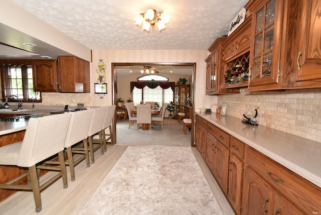 805 S James Ave, Fowler, IN 47944 - kitchen featuring brown cabinetry, a textured ceiling, glass insert cabinets, decorative backsplash, and light countertops
