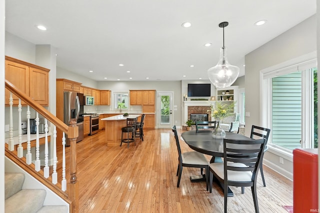 118 Royal Crest Dr, Fort Wayne, IN 46814 - dining room featuring a stone fireplace, light wood-style floors, recessed lighting, stairway, and plenty of natural light