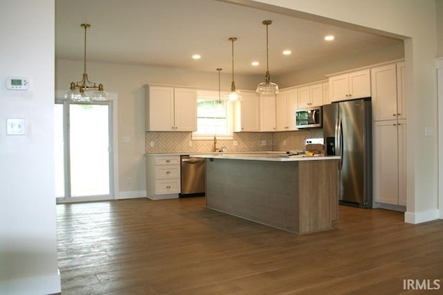 1001 E Clinton St, Frankfort, IN 46041 - kitchen featuring appliances with stainless steel finishes, backsplash, white cabinets, dark wood finished floors, and a center island