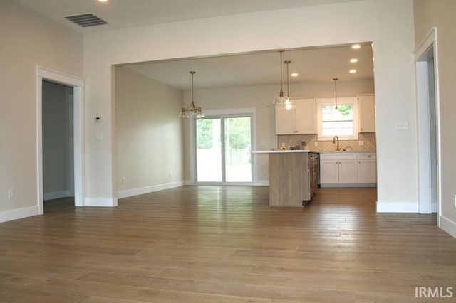 1001 E Clinton St, Frankfort, IN 46041 - kitchen featuring open floor plan, white cabinetry, light wood-style floors, light countertops, and backsplash
