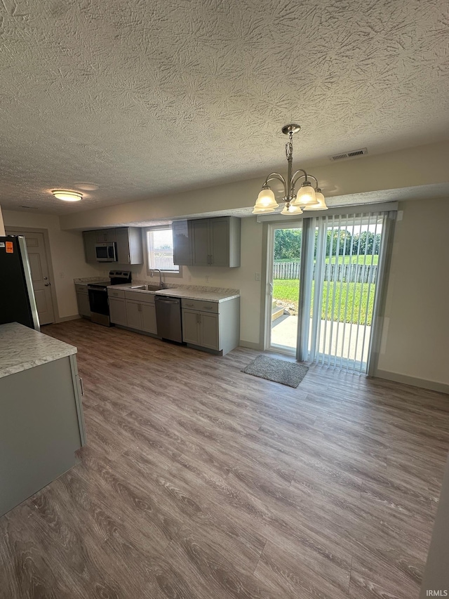 914 Braxton Dr N, Lafayette, IN 47909 - kitchen with appliances with stainless steel finishes, gray cabinetry, a chandelier, wood finished floors, and a textured ceiling