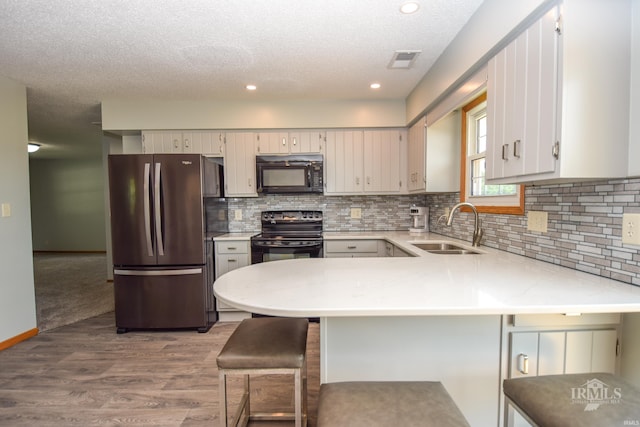475 Gillcrest Dr, Albany, IN 47320 - kitchen with black appliances, a peninsula, light countertops, wood finished floors, and tasteful backsplash