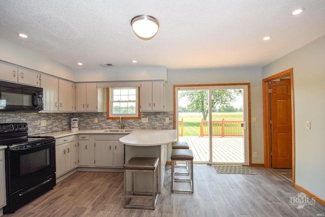 475 Gillcrest Dr, Albany, IN 47320 - kitchen featuring black appliances, light countertops, wood finished floors, a peninsula, and tasteful backsplash