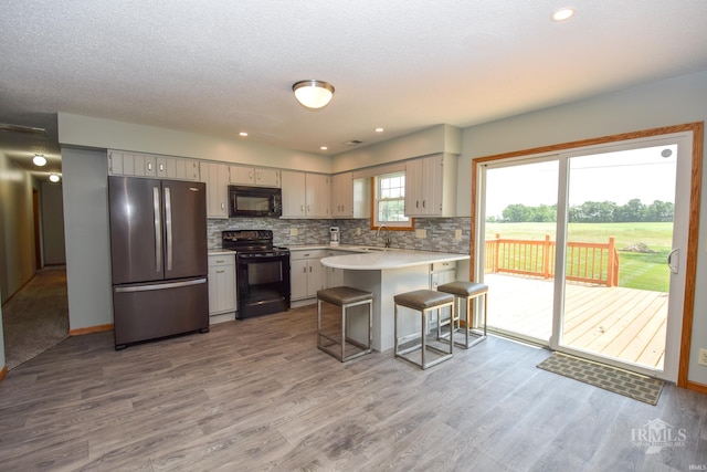 475 Gillcrest Dr, Albany, IN 47320 - kitchen featuring black appliances, a peninsula, light countertops, wood finished floors, and recessed lighting