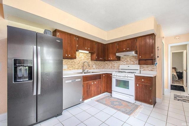 18055 Thomas Ln, Goshen, IN 46528 - kitchen featuring appliances with stainless steel finishes, under cabinet range hood, light countertops, decorative backsplash, and light tile patterned floors