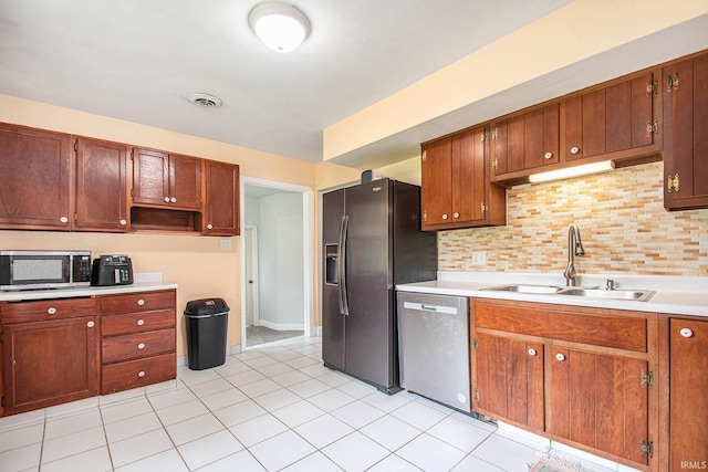 18055 Thomas Ln, Goshen, IN 46528 - kitchen with stainless steel appliances, light countertops, backsplash, light tile patterned floors, and brown cabinetry