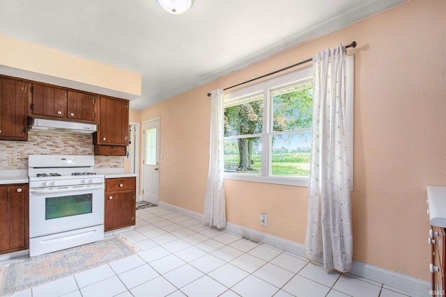 18055 Thomas Ln, Goshen, IN 46528 - kitchen with white gas range, under cabinet range hood, light countertops, tasteful backsplash, and light tile patterned floors