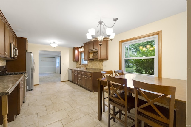 3617 Kirkfield Dr, Fort Wayne, IN 46815 - kitchen with stainless steel appliances, tasteful backsplash, a chandelier, dark countertops, and light stone finish floors