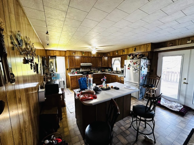 3886 N 1300 E, Loogootee, IN 47553 - kitchen featuring freestanding refrigerator, wooden walls, light countertops, exhaust hood, and healthy amount of natural light