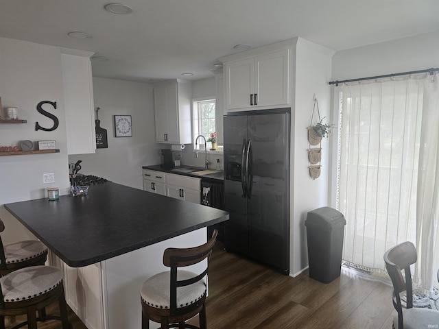 11016 Lakeview Rd, Kewanna, IN 46939 - kitchen featuring stainless steel fridge with ice dispenser, dark countertops, a peninsula, a kitchen bar, and dark wood finished floors
