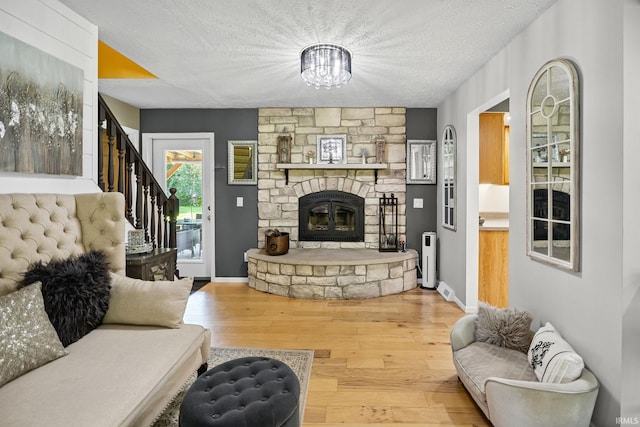 12856 W Bicycle Bridge Rd, Battle Ground, IN 47920 - living room featuring a textured ceiling, wood finished floors, stairs, a chandelier, and a stone fireplace