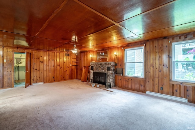 2200 S 460 E, Lagrange, IN 46761 - unfurnished living room featuring baseboard heating, carpet flooring, wood walls, a stone fireplace, and a ceiling fan