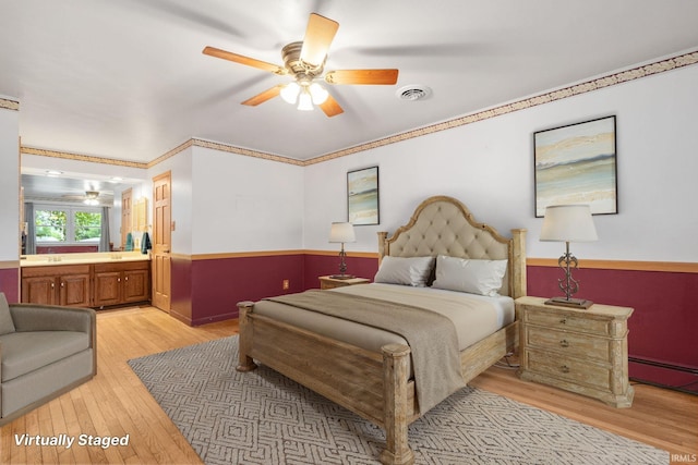 26247 Douglas Ave, Elkhart, IN 46514 - bedroom with light wood-style floors, wainscoting, baseboard heating, ensuite bath, and a ceiling fan