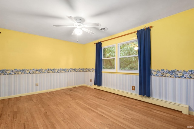26247 Douglas Ave, Elkhart, IN 46514 - unfurnished room with baseboard heating, wood finished floors, ceiling fan, and wallpapered walls