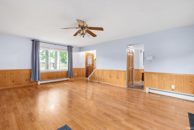 26247 Douglas Ave, Elkhart, IN 46514 - empty room with baseboard heating, a wainscoted wall, light wood-type flooring, a ceiling fan, and wooden walls