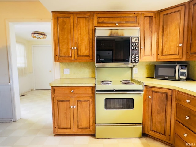 1028 N Wabash Ave, Marion, IN 46952 - kitchen featuring black microwave, electric range, light flooring, stainless steel microwave, and brown cabinets