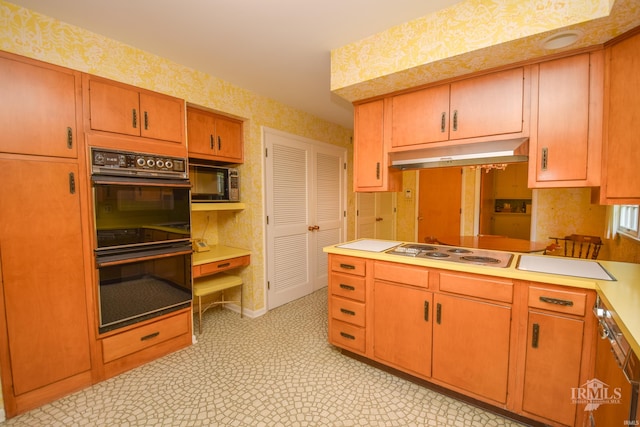 3400 W University Ave, Muncie, IN 47304 - kitchen with black appliances, under cabinet range hood, wallpapered walls, and light countertops