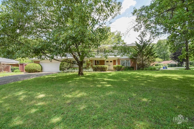 3400 W University Ave, Muncie, IN 47304 - view of front of home featuring driveway, a front lawn, an attached garage, and brick siding