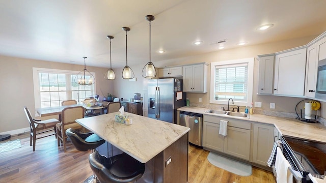 4229 New Birch Dr, Jasper, IN 47546 - kitchen featuring appliances with stainless steel finishes, a kitchen breakfast bar, a kitchen island, light wood-type flooring, and decorative light fixtures