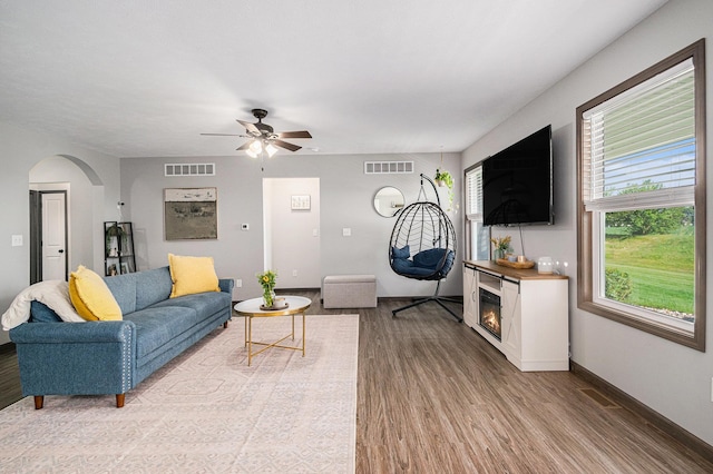 2010 Newbury Cir, Goshen, IN 46526 - living room featuring wood finished floors, a glass covered fireplace, a ceiling fan, and arched walkways